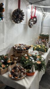 Présentation d'une table sur un marché de noël avec des créations de couronnes en fleurs séchées et fraîches à Vélizy-Villacoublay 78
