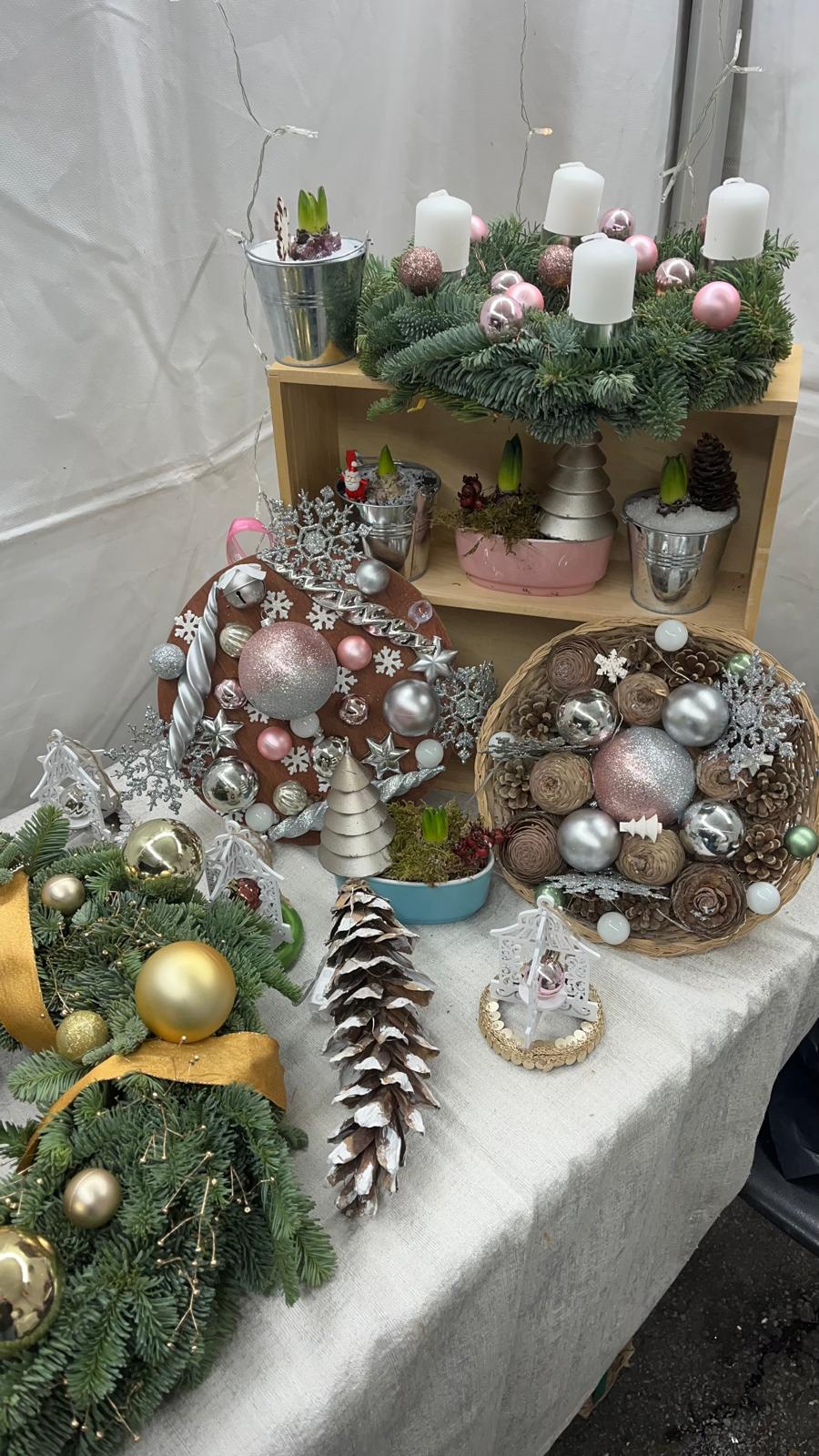 Présentation d'une table sur le marché noël de couronnes fraîches et séchée, compositions de jacinthes féériques